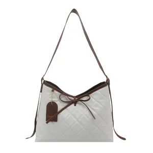 Quilted white tote bag with brown contrast trim and bow accent for daily commute