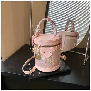 Dettaglio borsa a secchiello rosa in pizzo con manico in foulard e ciondoli