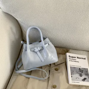 Detail of light blue bucket bag with silver buckle strap on a cozy beige sofa