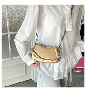 Details der metallisch goldenen Mondsichel-Tasche mit Silberkette und Logo-Prägung