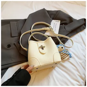 Detail view of cream bucket bag with lychee texture and metallic twist lock closure