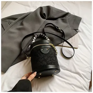 Dettaglio borsa a secchiello in pizzo nero con manico foulard e borchie dorate