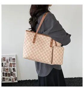 Detail view of a monogrammed tote bag set with matching pouch on a fashion model