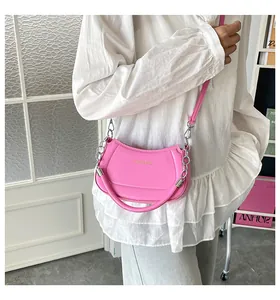 Detailansicht der rosa Halbmond-Tasche mit silberner Kette und feiner Ledertextur-Oberfläche