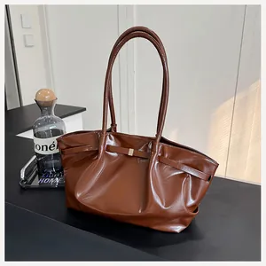 Détail d'un sac seau en cuir verni marron avec finition brillante et boucle dorée