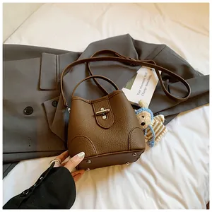 Close-up of brown litchi pattern leather bucket bag with metal turn-lock and protective feet