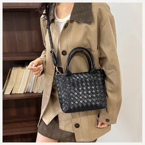 Close-up of black woven leather bucket bag featuring a detachable adjustable shoulder strap