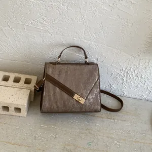 Detailed close-up of retro brown handbag with vertical texture and gold metal buckle