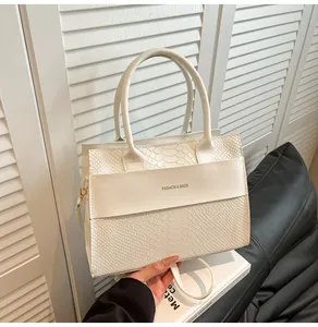 Dettaglio borsa a mano bianco crema con trama a serpente e logo fashion stampato