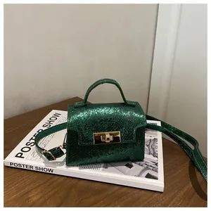 Close-up of green snake-print mini handbag with gold twist lock on a wooden table
