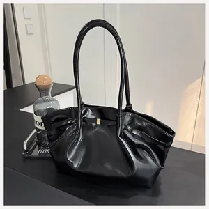 Détail d'un sac cabas en cuir verni noir avec boucle dorée et plis élégants
