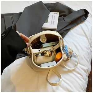 Close-up of white pebble leather bucket bag showing interior space and cute bear charm