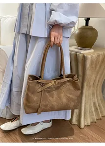 Close-up of vintage brown leather tote bag with decorative buckle and dual handles