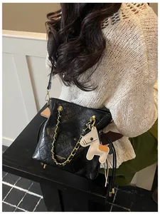 Detail of black quilted leather bucket bag with gold chain strap and pony charm accent