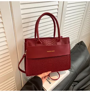 Dettaglio della borsa rossa con goffratura a coccodrillo e scritte dorate rifinite