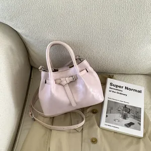 Top view of light pink leather bucket bag on trench coat showing strap buckle detail