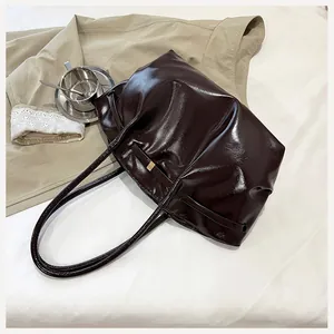 Détail du cabas en cuir verni marron foncé avec élégant nœud et texture plissée