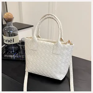 Detail of white woven leather bucket bag featuring gold hardware and a detachable strap