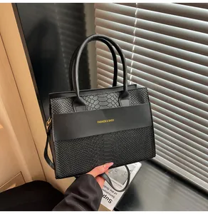 Dettaglio della borsa nera in ecopelle con motivo a coccodrillo e scritte dorate