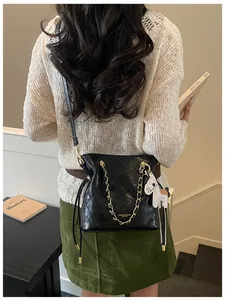 Close-up of black quilted bucket bag with gold chain strap and a white horse charm