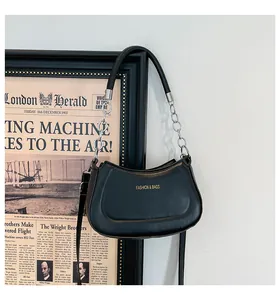 Detailaufnahme schwarze Umhängetasche mit silberner Metallkette und goldenem Aufdruck