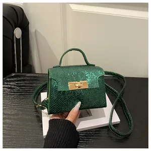 Detail of dark green snake-embossed leather mini bag with golden metal rotating lock