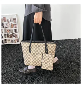 Overhead view of beige tote set with monogram pattern and black leather straps