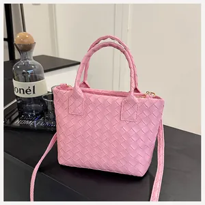 Detailed view of pink woven leather tote bag with Intrecciato pattern on dark wood surface