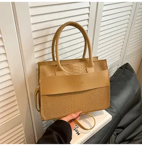 Dettaglio ravvicinato della borsa beige in ecopelle goffrata serpente con logo dorato