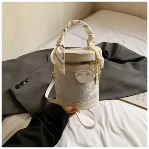 Dettaglio borsa a secchiello in pizzo crema con foulard decorativo e dettagli dorati