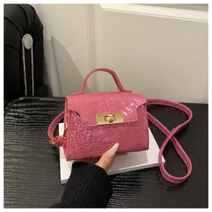 Detail of pink croc-embossed leather handbag with a polished gold metallic twist lock