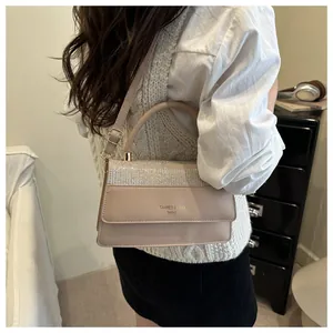 Detail view of beige crossbody bag with shimmering crystal flap and golden hardware