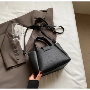 Detail der schwarzen Bucket-Bag aus Leder mit Griffen auf einem schicken Blazer