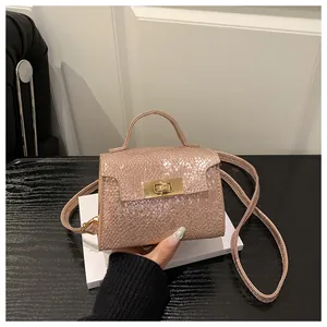 Detail of rose gold snakeskin texture handbag with gold twist lock and top handle