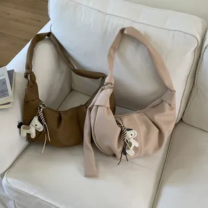 Detail von Mondsicheltaschen in Braun und Beige mit Pferdeanhängern auf weißem Sofa