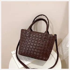 Close-up of the intricate dark brown woven leather texture and sturdy handle of the bucket bag