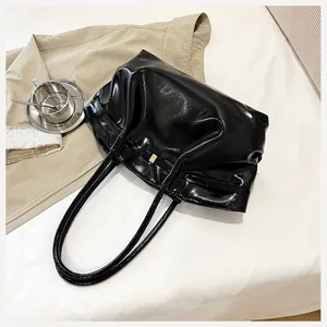 Vue détaillée du sac cabas en cuir verni noir avec boucle dorée et doubles bandoulières