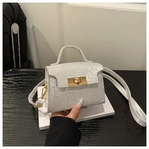 Detail of silver textured mini bag featuring gold twist lock and adjustable shoulder strap