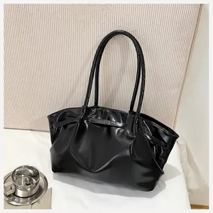 Détail du sac seau plissé en cuir verni noir brillant avec de longues bandoulières élégantes
