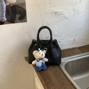 Detail of black tote bag with strap buckle and a cute teddy bear plush charm