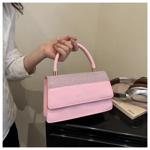 Detail of pink leather handbag featuring glitter flap and branded metallic handle