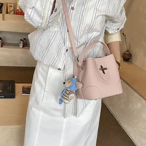 Pink pebbled leather bucket bag with top handle and bear charm pendant