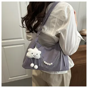 Bolso hobo morado con cadena de perlas y colgante de nube en el hombro de la modelo