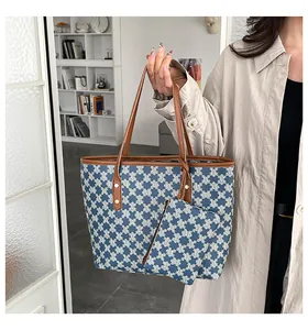 Close-up of retro checkered tote bag with blue 'M' print and brown leather handles