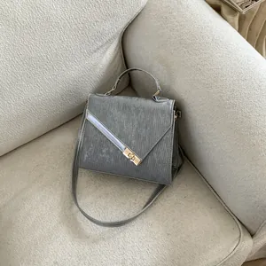 Detail of grey crossbody bag featuring unique vertical texture and gold twist lock