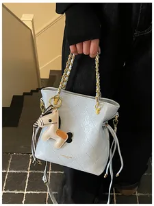 Detail of light blue quilted bucket bag with gold chain and horse charm accessory