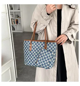 Detailed view of the large capacity tote and matching pouch with blue M-pattern and brown straps