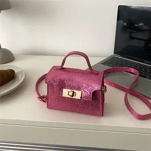 Metallic pink snake texture mini handbag with gold clasp on desk with office accessories