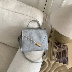 Detail of silver brushed leather handbag with golden rectangular lock and handle
