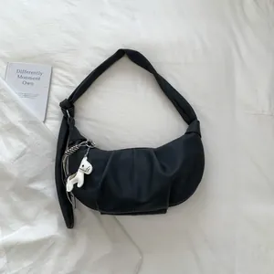 Detailansicht der schwarzen Raff-Hobo-Tasche mit weißem Pferdeanhänger auf Weiß